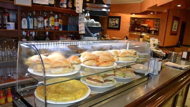Un expositor de alimentos con varios sándwiches y una tortilla.