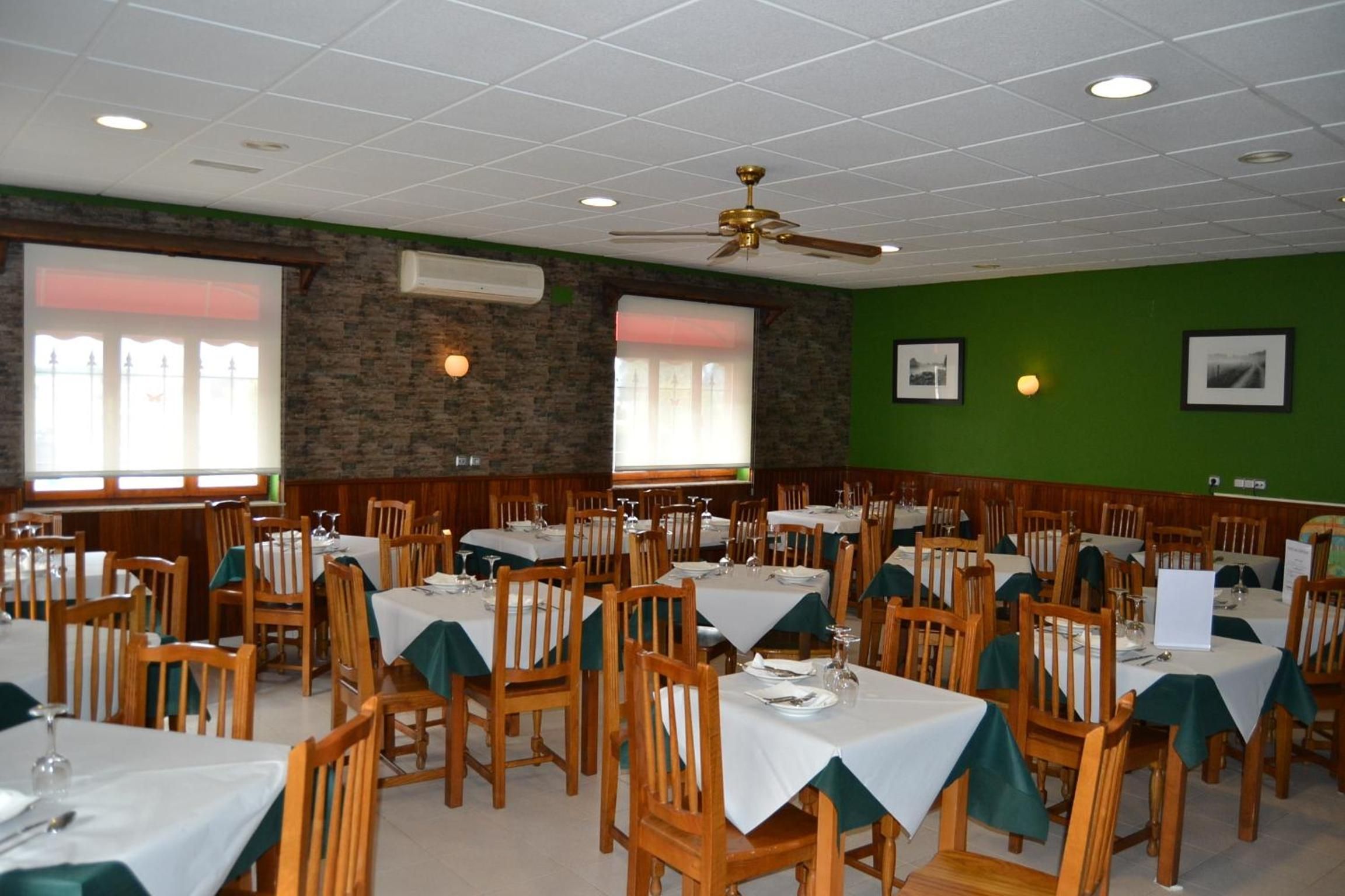 Un restaurante con varias mesas y sillas, unidades de aire acondicionado y un ventilador de techo.