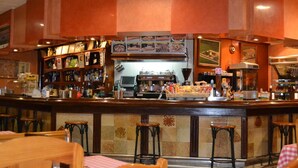 Una zona de bar con mostrador, taburetes y una selección de aperitivos.