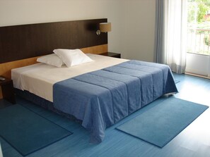 A hotel room with a bed, a nightstand, a lamp, and a view of the outdoors. - Hotel Rural Solar Das Freiras (Figueiró dos Vinhos)
