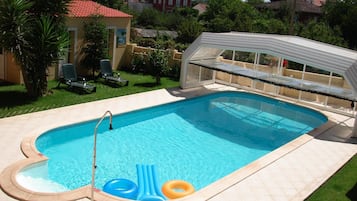 A rectangular swimming pool with a diving board, surrounded by a tiled deck.