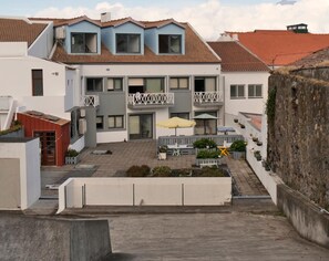 Een meerlaags woongebouw met balkons, een binnentuin met buitenmeubilair en een stenen muur.