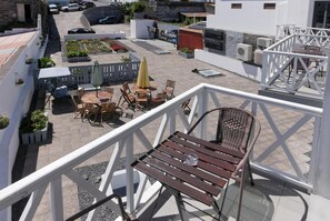 Een terras op het dak met buitenmeubilair, een uitzicht op de straat en een witte balustrade.