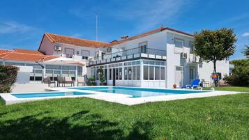 A modern two-story house with a swimming pool, outdoor seating, and a well-maintained lawn.