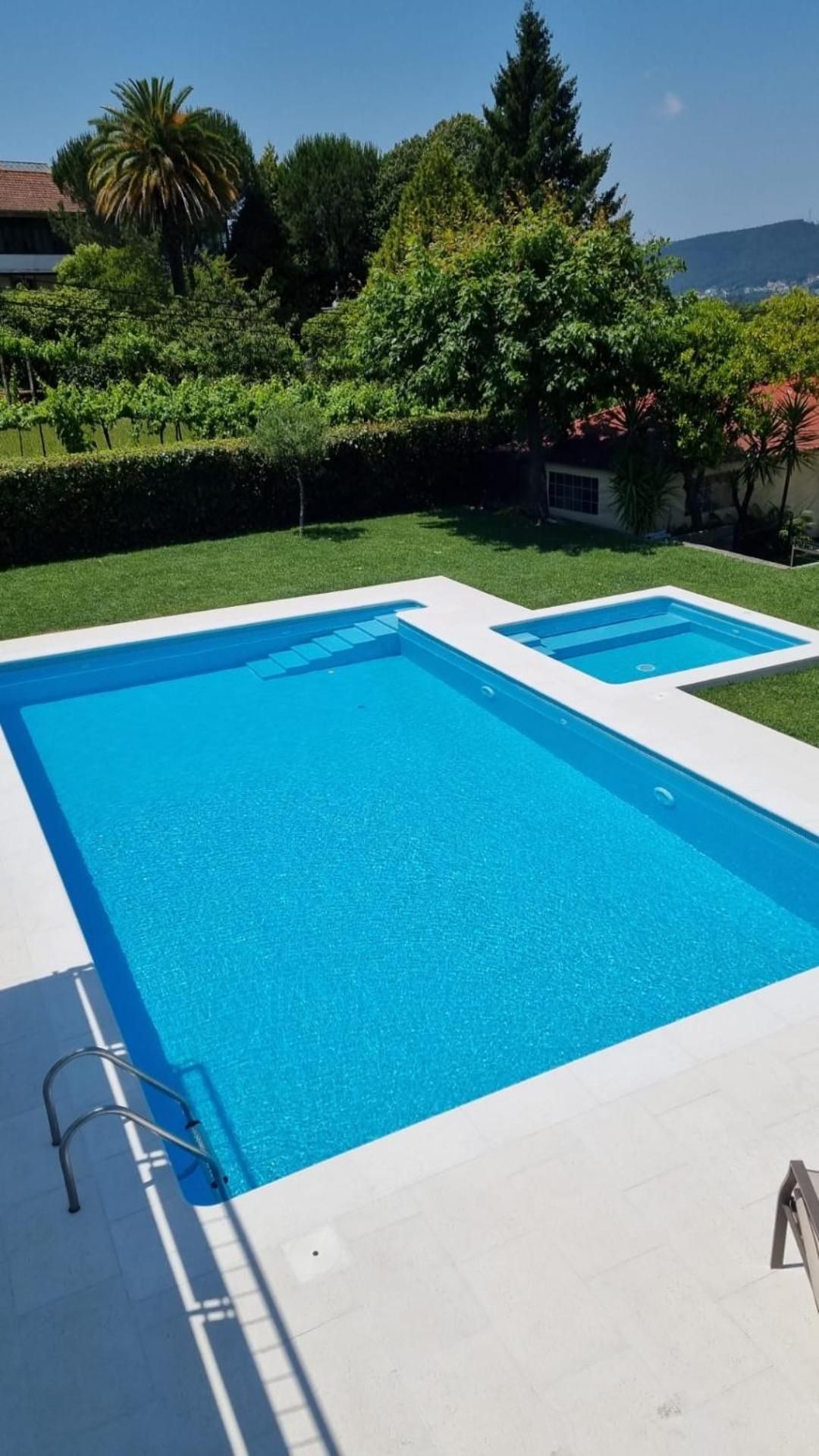 Une piscine rectangulaire à l’eau d’un bleu limpide, entourée d’une terrasse blanche.