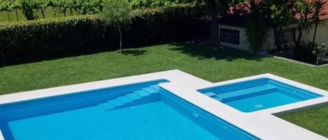 Una piscina rectangular con superficie de agua azul cristalina, rodeada por una terraza blanca.
