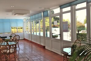 A covered outdoor seating area with tables and chairs, large windows, and a view of the outdoors. - Hotel Solar Das Laranjeiras (Vale de Cambra)