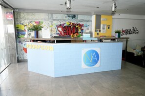A reception area with a graffiti wall, a reception desk, and a sign for New Art Palma Beach Hostel. - New Art Hostel Albergue Juvenil (Palma de Mallorca)