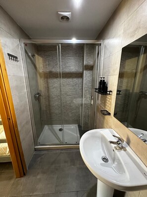 A modern bathroom with a glass-enclosed shower, a white sink, and a large mirror. - New Art Hostel Albergue Juvenil (Palma de Mallorca)