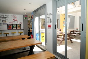 An interior with wooden tables and a wall decorated with coffee-related words and images. - New Art Hostel Albergue Juvenil (Palma de Mallorca)