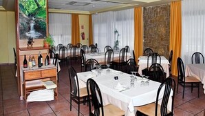 A dining area with multiple tables and chairs, a buffet station, and a stone wall.