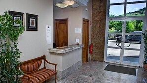 A reception area with a bench, a reception desk, a fire extinguisher, and a door leading outside.