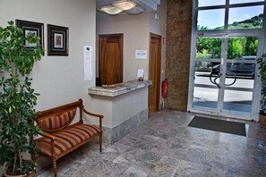 A reception area with a bench, a reception desk, a fire extinguisher, and a door leading outside.