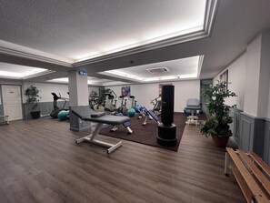 Ein Fitnessraum mit Trainingsgeräten, einem Boxsack und einer Bank.