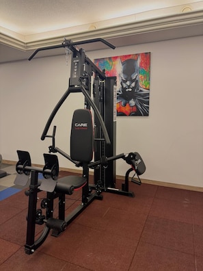 A gym with a bench press, a squat rack, and a pull-up bar. - Logis Hotel Spa La Poste (Vitry-le-Francois)