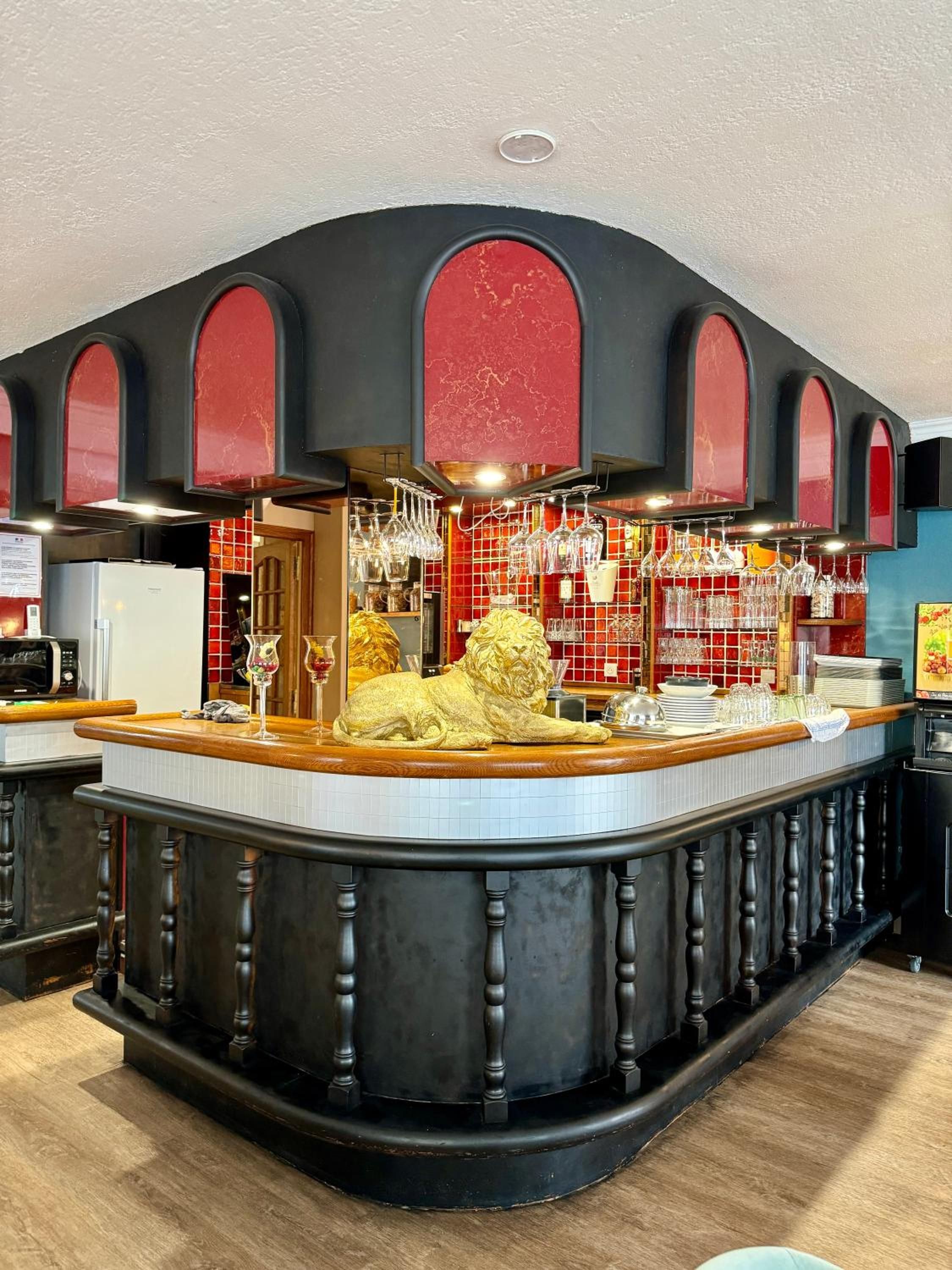Eine Bar mit einem Löwenstatuen-Zentrum, einem Weinkühlschrank und einer gefliesten Rückwand.