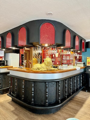 A bar area with a lion statue centerpiece, a wine rack, and a tiled backsplash. - Logis Hotel Spa La Poste (Vitry-le-Francois)