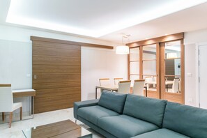 A modern living room with a sofa, a dining table, and chairs. - Tango Suites Cumbuco (Caucaia)