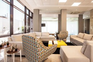 Ein modernes Interieur mit einer Couch, einem gemusterten Sessel und einem gelben Couchtisch.