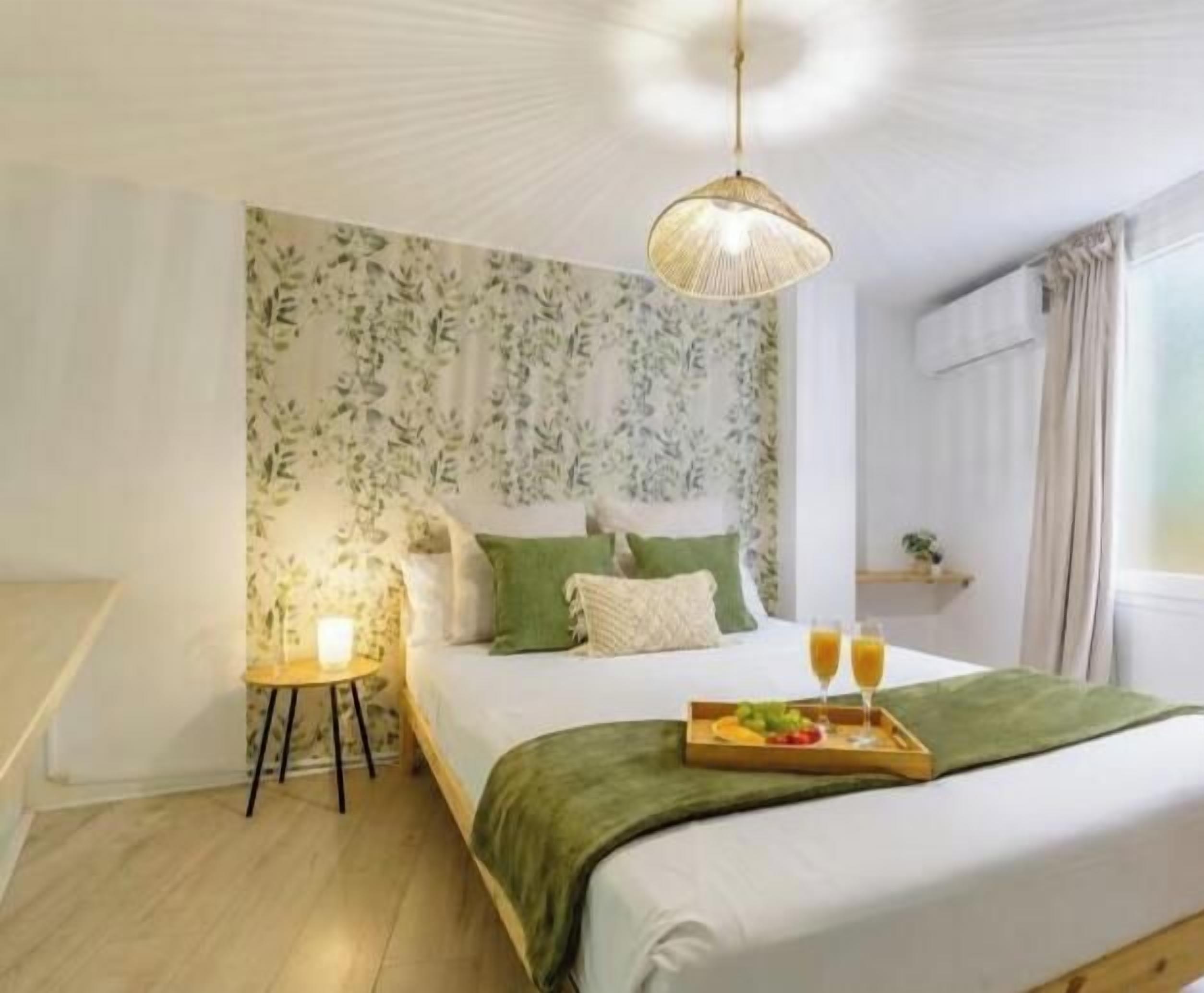 Ein Schlafzimmer mit einem Bett, einem Nachttisch, einer Lampe sowie einem Tablett mit Speisen und Getränken.