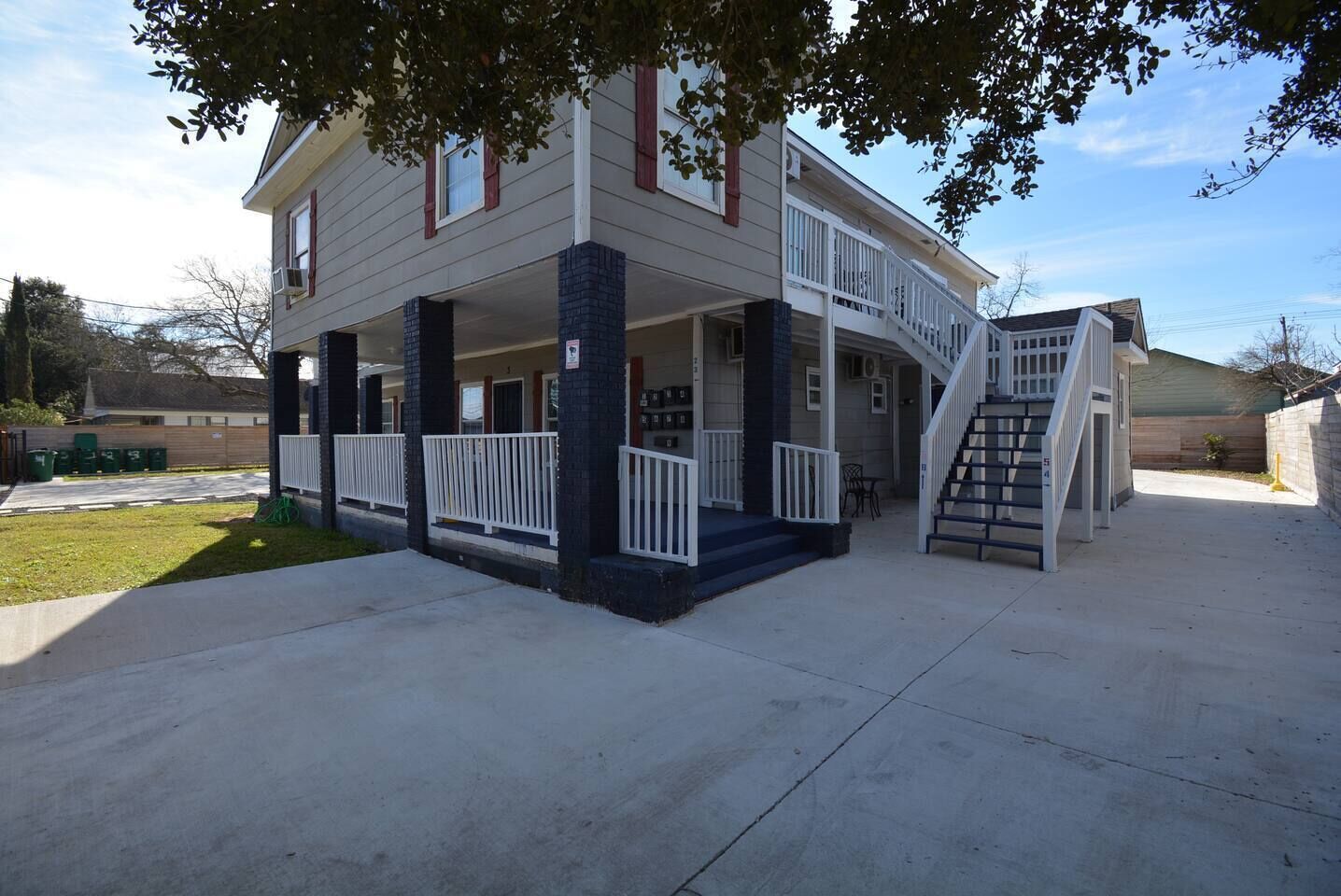 A two-story house with a covered porch, a staircase, and a small outdoor seating area.