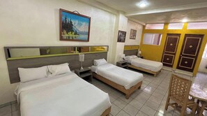 Una habitación de hotel con tres camas individuales, una mesa de comedor y una silla.