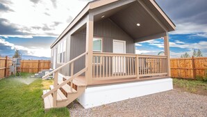 A single-story building with a covered porch, a staircase, and a fenced backyard.