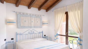A bedroom with a bed, bedside tables, a window with curtains, and a wall-mounted light fixture.