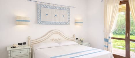 Un dormitorio con cama, mesitas de noche, una obra de arte en la pared y vistas a través de un ventanal.