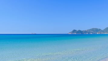 A clear blue sea with a distant island and mountains.
