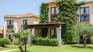 Un edificio con tetto in tegole, un portico coperto e un giardino con palme e arbusti.