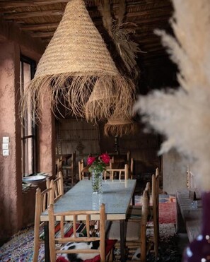 A rustic dining area with a wooden table, chairs, and a hanging thatch. - Atlas Aura (Marrakech)