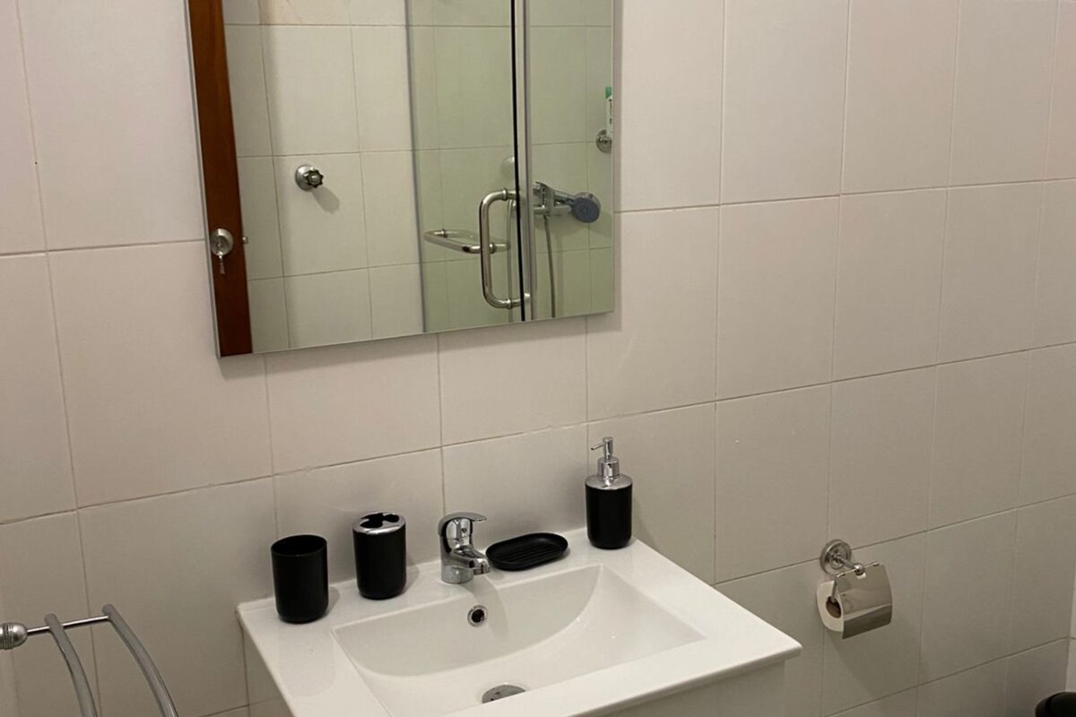 Casa de banho com uma pia branca, um espelho e um porta-toalhas.