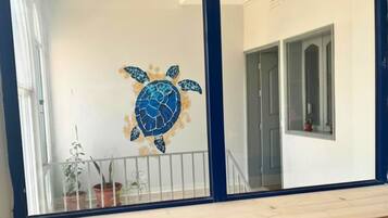 Ein Zimmer mit einem großen Fenster, einer Tür und einer Wand mit einem Wandgemälde von einer Meeresschildkröte.