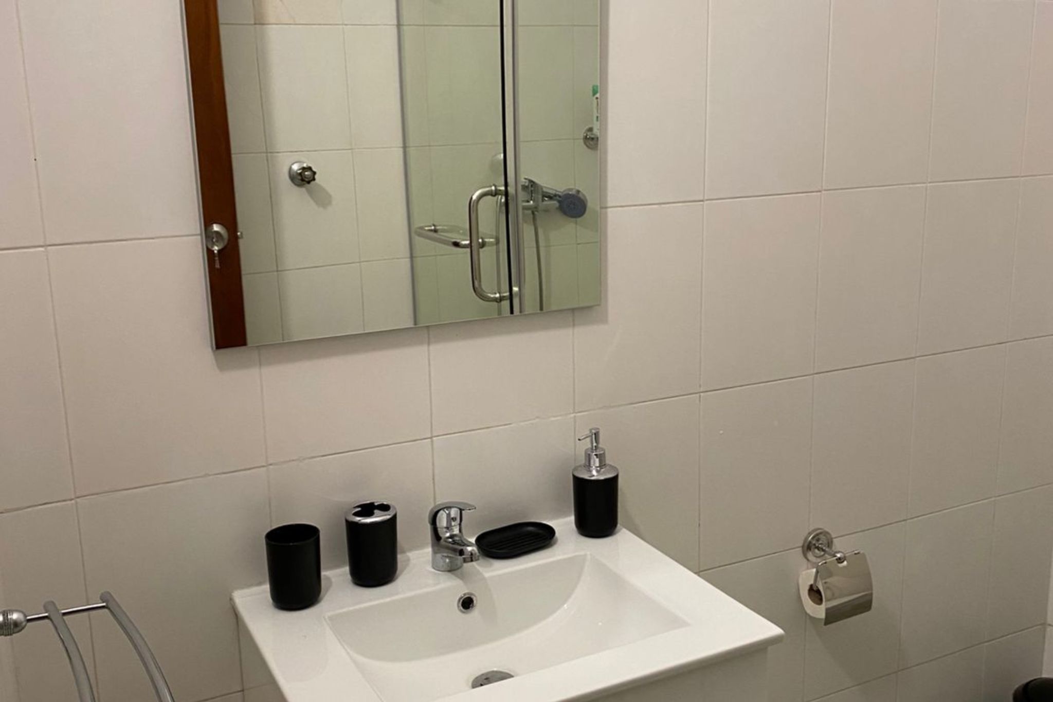 A bathroom with a white sink, a mirror, and a towel rack.