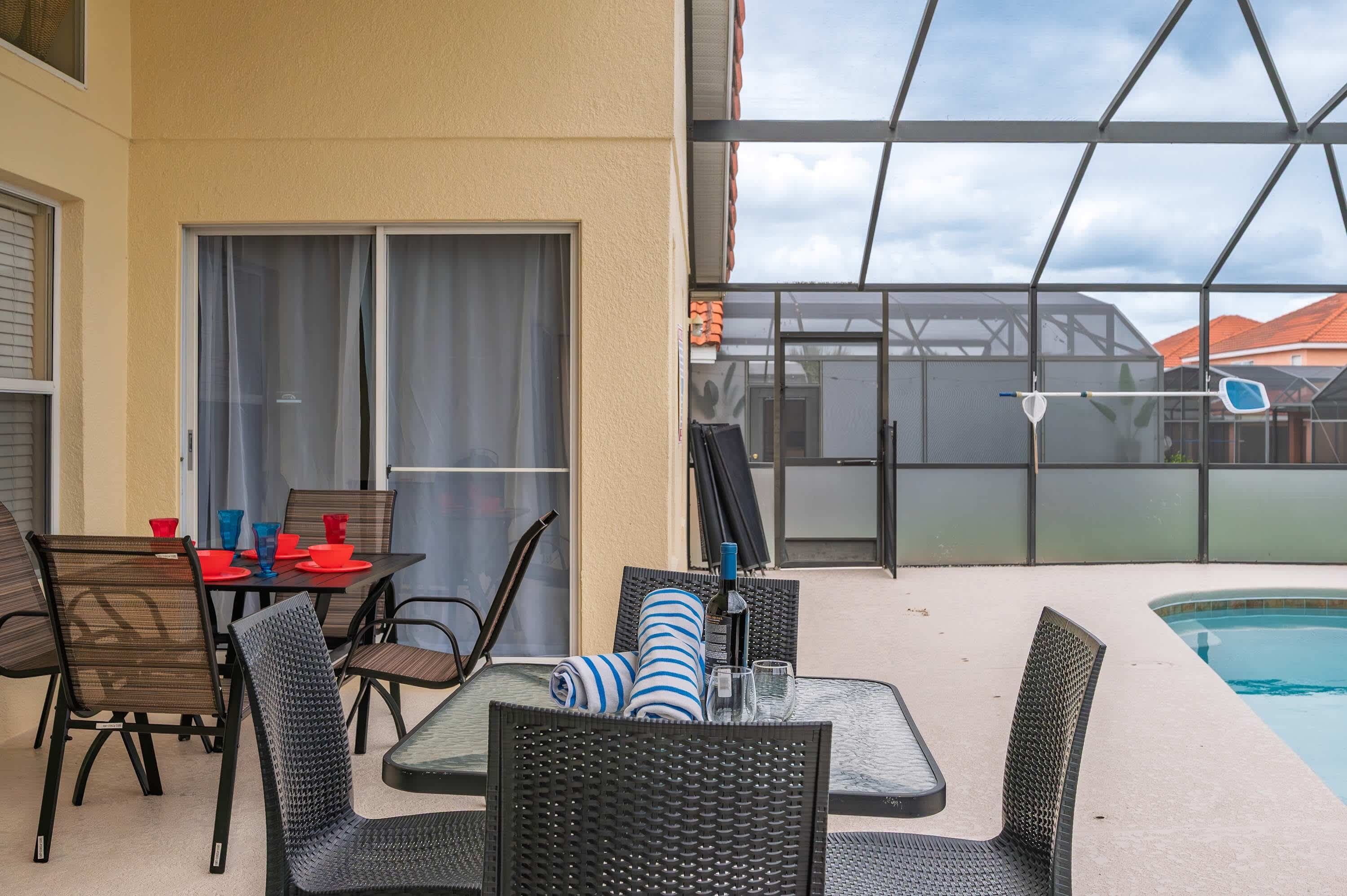 Eine Terrasse im Freien mit Pool, einem überdachten Sitzbereich mit Stühlen und Tisch sowie einer Glasschiebetür zu einem überdachten Bereich.