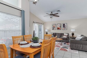 Ein modernes Wohnzimmer mit Essbereich, Deckenventilator und Kunstwerken an den Wänden.