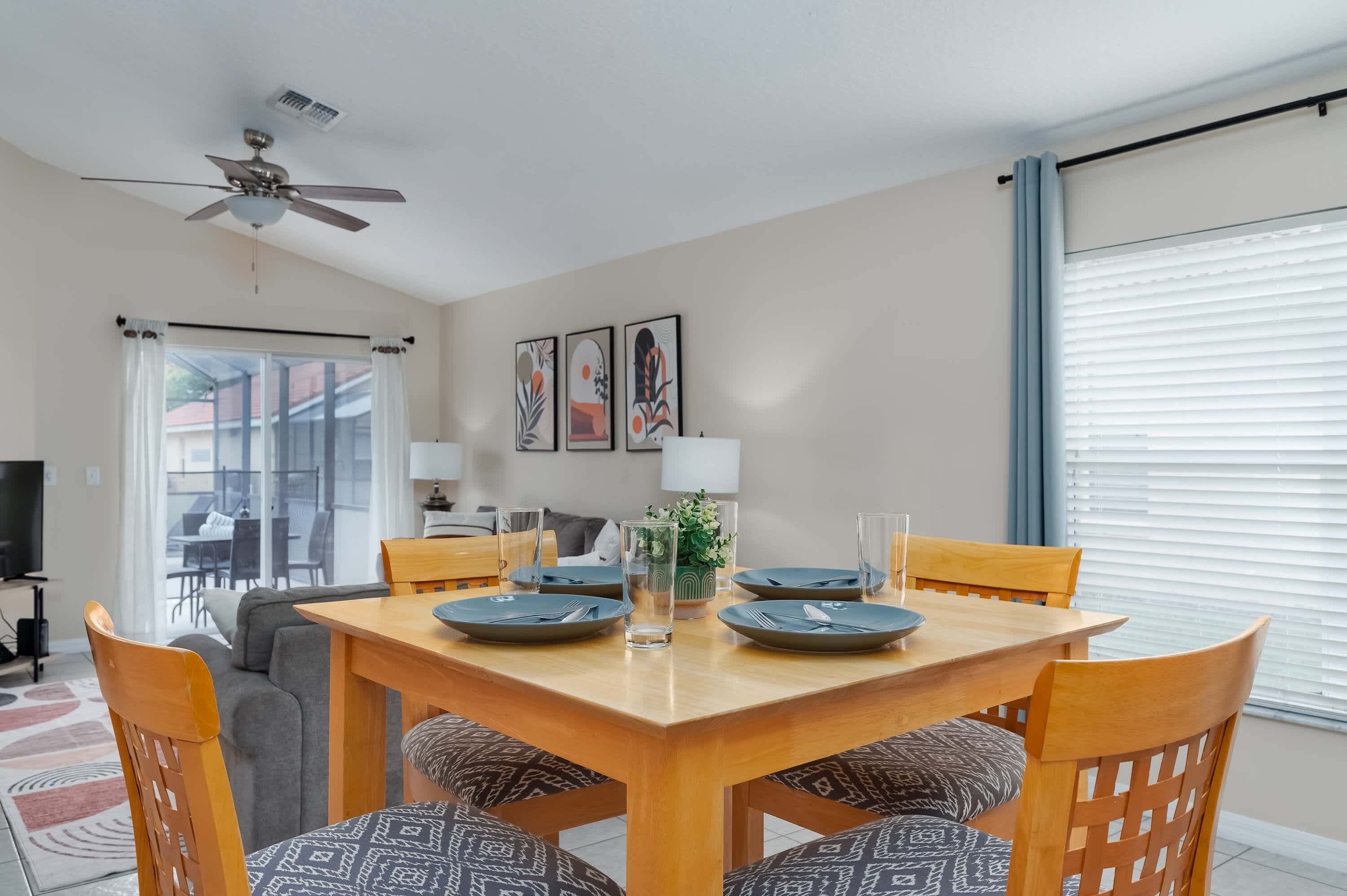 Un comedor con una mesa de madera, cuatro sillas y un ventilador de techo.