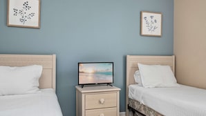 Camera da letto con due letti, un comodino con televisore e opere d'arte alle pareti.