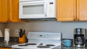 Una cucina con un piano cottura bianco, un forno a microonde e una macchina per il caffè.