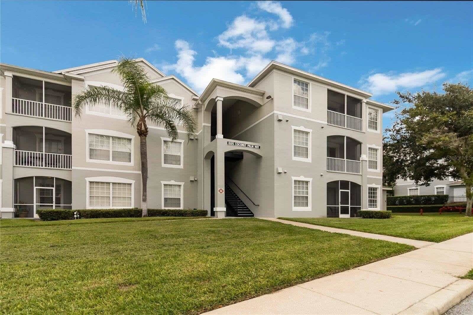 A two-story residential building with a central entrance, a staircase, and a well-maintained lawn.