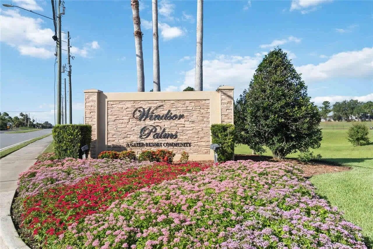 A sign for Windsor Palm's gated resort community with a landscaped flower bed in front.