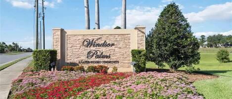 Un panneau indiquant l’entrée du complexe résidentiel fermé de Windsor Palm, avec un parterre de fleurs aménagé devant.