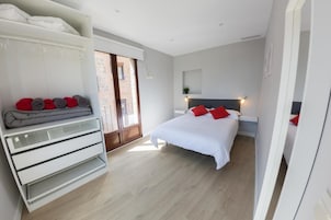 Un dormitorio con cama, armario y puerta que da a un balcón.