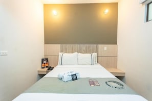 A hotel room with a bed, a bedside table, a wall-mounted light, and a framed picture. - Mandala Medellin Botero By Gyc Hotels (Medellín)