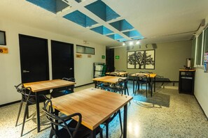A conference room with tables and chairs, a painting on the wall, and a ceiling with blue panels. - Mandala Medellin Botero By Gyc Hotels (Medellín)