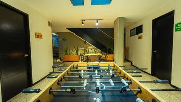 A corridor with a foosball table, doors numbered 201 and 206, and a green exit sign.