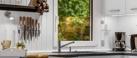 A modern kitchen with a large window, a sink, and a variety of knives.