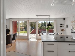 Eine moderne Küche mit einer großen Kochinsel, Schiebegläsern zu einer Terrasse und einem Essbereich mit Stühlen.
