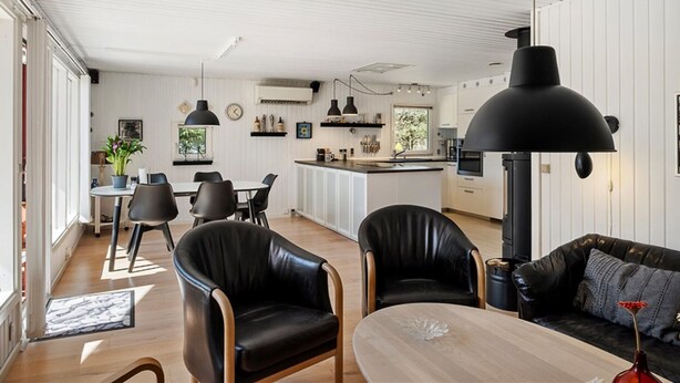 Een moderne keuken met witte kasten, een zwarte hanglamp en een groot fornuis.